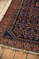 Corner of Vintage Hamadan rug, navy Herati pattern, blush vine border, frayed fringe.