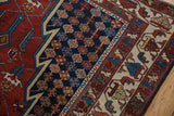 Intricate floral motifs in the navy border of a vintage Persian Hamadan rug.