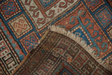 Hand-knotted brown foundation, ivory fringe, and visible mended area of the antique Kurdish rug.