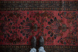 Boots on vintage Lilihan rug, raspberry red field, asymmetric floral vines, mir serbend border.