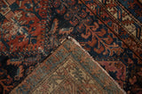 Vintage Mehreban rug folded, revealing hand-knotted foundation, tattered edge, and worn cherry red, cobalt blue pile.