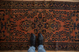 Dusty raspberry Lilihan runner with ornate floral patterns, person's feet, and subtle stain.