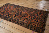 Detailed view of the Lilihan runner's dusty raspberry field, navy floral border, and intact side cord.