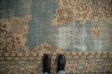 Feet on vintage Sparta carpet, dusty blue abrashed field, cream trefoil motifs, visible foundation.