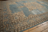 Corner of vintage Turkish Sparta carpet showing abrashed dusty blue field, cream spandrel, and patterned border.