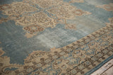 Corner view of vintage Sparta carpet with abrashed dusty blue field, cream motifs, and low pile.