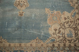Dusty blue Sparta carpet detail: cream spandrel pattern, dark motifs, and visible knot heads.