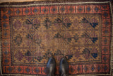 Antique Belouch rug's geometric aubergine, camel, navy field with foundation wear and blush border.