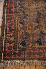 Detail of antique Belouch rug's geometric blush border, patterned field, and beige fringe.