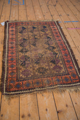 Antique Belouch rug corner, blush border with navy geometric accents, worn aubergine field.