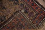 Folded antique Belouch rug detail revealing low pile, knot heads, and secured, frayed camel and aubergine ends.