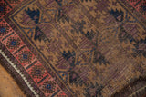 Detailed view of antique Belouch rug's camel field, aubergine, navy serrated floral motifs and blush border.
