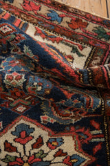 Intricate Herati fish pattern in navy, ivory, and blush on folded vintage Borchalou rug pile.