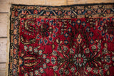 Vintage Lilihan rug corner with cherry red field, scrolling vines, and intact selvage.