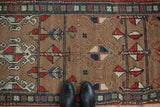 Close-up of antique Northwest Persian runner, short camel brown pile, geometric pinwheel motifs, navy, red, ivory.