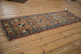 Northwest Persian runner's short fringe, camel field, and red, navy pinwheel motifs.