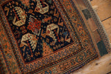 Antique Afshar rug corner: navy field, serrated dragon motifs, terracotta border, woven end.