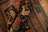 Antique Afshar rug's intricate terracotta and navy patterns, hand-knotted pile texture, and visible selvedge.