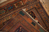 Antique Afshar rug folded corner, revealing terracotta, blue, green patterns and woven reverse.