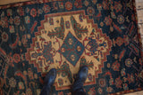 A standing perspective showing the scale of a vintage Persian Borchalou rug's stepped medallion and aquatic motifs.