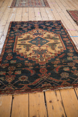 Angled view of the vintage Borchalou rug, highlighting the stepped medallion and stylized figures on the navy field.