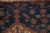Stylized dragons and a small bird on the navy blue pile of a vintage Borchalou rug.