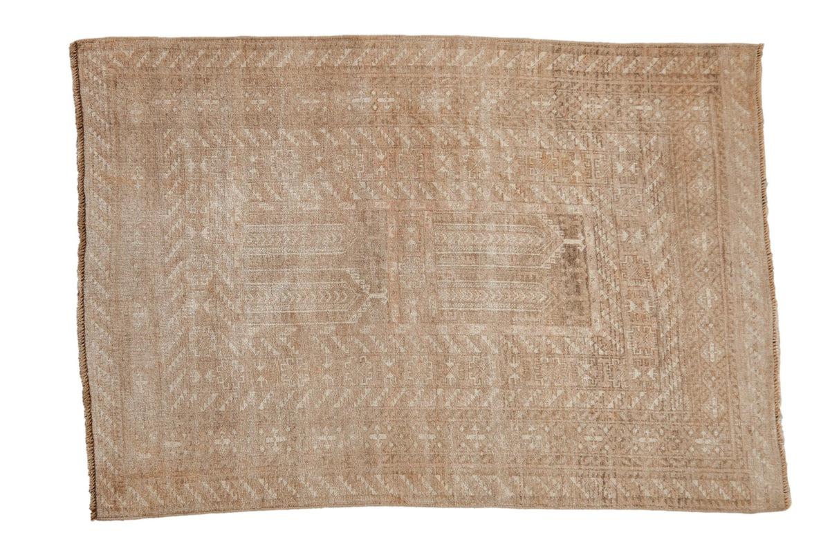 Vintage distressed Turkmen rug with faint geometric panels and layered borders in neutral sand and beige tones.