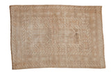 Vintage distressed Turkmen rug with faint geometric panels and layered borders in neutral sand and beige tones.