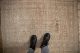 A top-down view of a distressed Turkmen rug showing its low pile and sandy neutral tones.