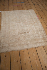 A distressed Turkmen rug with intricate, tonal geometric patterns shown from an overhead angle.