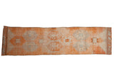 Distressed vintage Kurd runner with repeating geometric panels in pale tangerine, ivory, and silver.