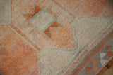 Distressed vintage Kurd runner detail: geometric orange, ivory, and silver starburst guls.