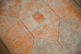 Distressed vintage Kurd rug's geometric starburst guls and hook motif in pale tangerine and ivory.