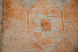 Distressed pile of vintage Kurd rug, displaying geometric guls in pale tangerine and ivory.