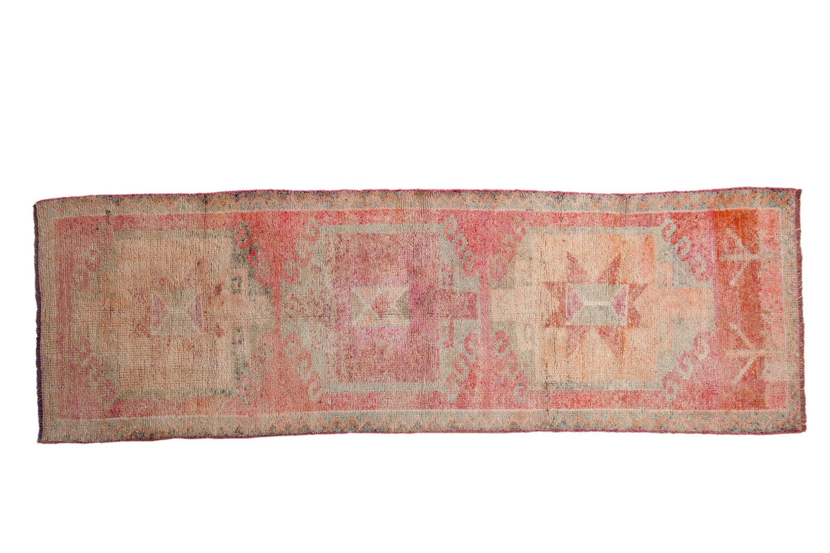 Distressed vintage Kurd runner with triple geometric medallions in fuchsia, rose, and silvery tones.