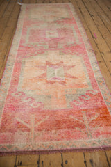 Angled perspective showing the full length of the distressed vintage Kurd runner and its repeating medallions.