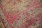 A close view of the short, textured pile on a distressed Kurd rug in raspberry and silver tones.