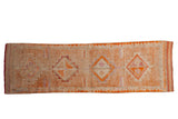 Distressed vintage Kurd runner with tangerine and raspberry diamond medallions on an abrashed ground.