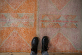 Distressed Kurd rug runner with short pile, tangerine and faded primitive patterns, under boots.
