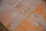 Distressed Kurd runner pile, highlighting tangerine orange, fuchsia, and ivory geometric abrashes.