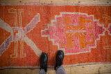 Primitive medallions and color abrashes in tangerine orange and fuchsia on a vintage Kurd rug.