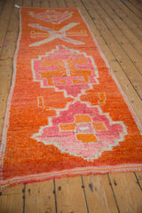Distressed Kurd runner from an angle, showcasing vibrant fuchsia and tangerine primitive medallions.