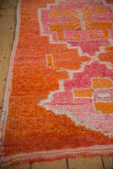 Angled close-up of a distressed Kurd runner's pile with tangerine and fuchsia geometric patterns.
