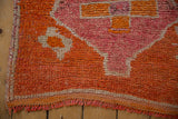 Corner of a distressed Kurd runner with low textured pile and secured side cord.
