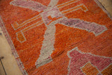 Close-up view of the hand-knotted pile, showing color abrashes in the tangerine and fuchsia medallion.