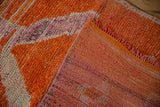 Corner view of a distressed Kurd rug showing the tangerine hand-knotted pile and plain weave back.