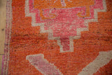 Visible knot heads and color abrashes in fuchsia and orange on a distressed vintage Kurd rug runner.