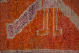 A close view of the primitive, hand-knotted pile showing tangerine and fuchsia abrashes.