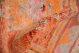 Intact side cord selvage showing the hand-knotted texture in tangerine orange and rust.