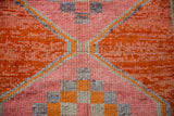 Hand-knotted Kurd rug detail, showing vibrant tangerine, pink, and faded purple checker design.